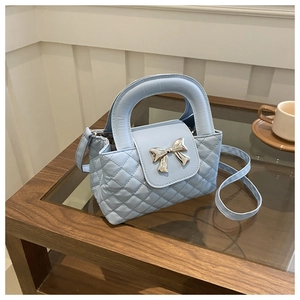 Detail of light blue quilted handbag featuring silver bow buckle and elegant top handle