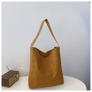 Dettaglio di una borsa tote in pelle scamosciata marrone con una radio vintage