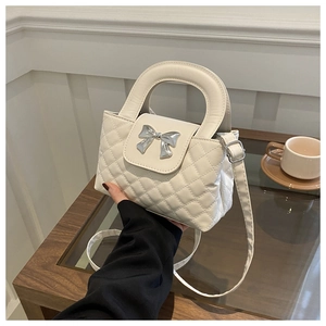 Détail du sac à main matelassé blanc avec nœud argenté et bandoulière réglable