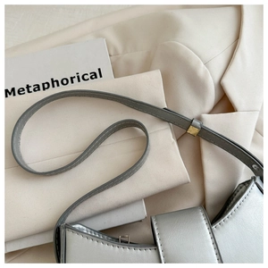 Detail of silver metallic leather shoulder bag with fine stitching and gold buckle hardware