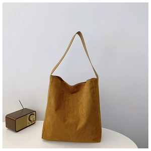 Dettaglio della borsa a spalla vintage in pelle scamosciata marrone su tavolo bianco