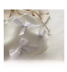 Détail du sac seau blanc en cuir avec nœuds en satin et bandoulière chaîne dorée