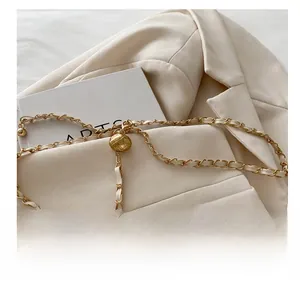 Détail de la bandoulière en chaîne dorée entrelacée de cuir blanc et boucle boule matelassée