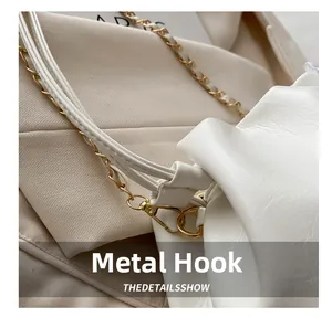 Détail du fermoir mousqueton doré et de la bandoulière en chaîne et cuir sur un sac blanc