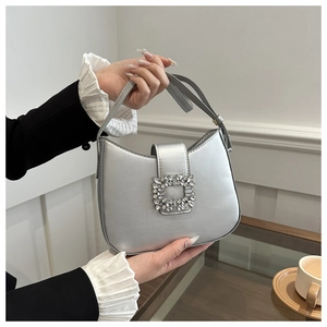 Detail of silver metallic crescent bag featuring a large square rhinestone buckle on strap