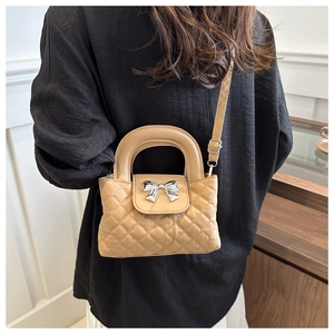 Sac bandoulière matelassé avec nœud métallique porté par un mannequin en intérieur