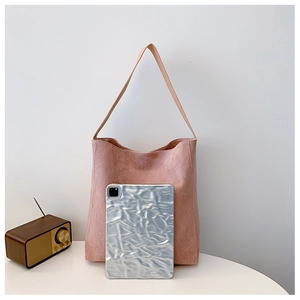 Dettaglio borsa tote rosa in pelle scamosciata opaca con tracolla marrone e design essenziale