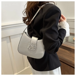 Close-up of a silver metallic shoulder bag featuring a classic rectangular rhinestone buckle