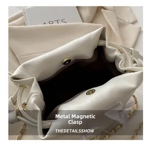 Détail du sac en cuir blanc avec boucle magnétique et bandoulière chaîne dorée