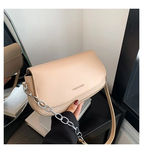 Detail of minimalist cream saddle bag featuring embossed fashion logo and chain strap