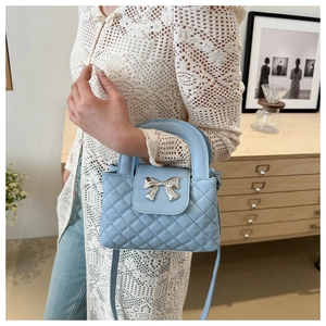 Détail d'un sac à main matelassé bleu clair avec boucle noeud argenté et poignée