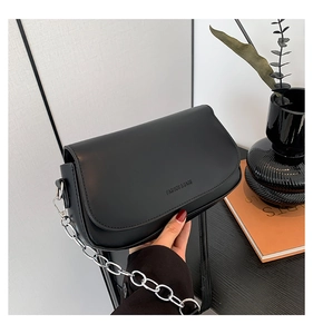 Detail of black saddle bag with silver chain strap and fashion text engraving