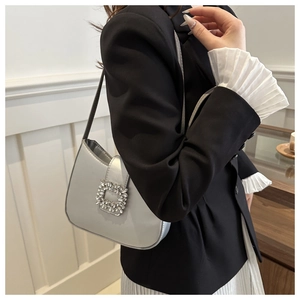 Silver-grey leather underarm bag with a crystal buckle shown on a model's shoulder