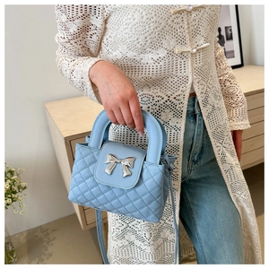Détail du mini sac matelassé bleu clair avec noeud argenté et poignée supérieure