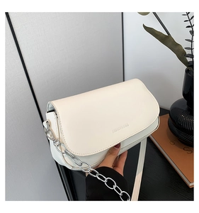 Close-up of minimalist cream leather saddle bag with silver chain and FASHION & BAGS text