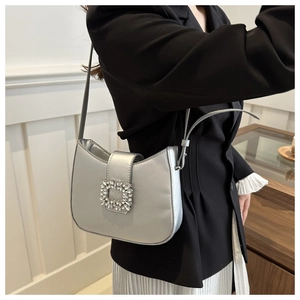 Detail of silver baguette bag featuring a sparkling crystal buckle and slim shoulder strap
