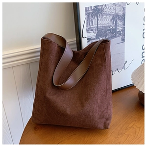 Dettaglio della borsa tote marrone opaco con tracolla in pelle color caffè liscia sul tavolo