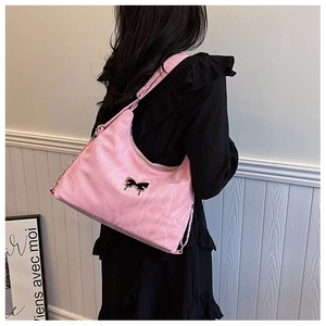 Pink Hobo tote bag with black bow detail and metal chain strap on a model