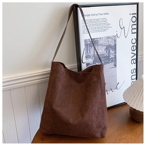 Dettaglio della borsa tote in pelle scamosciata caffè contro una parete artistica