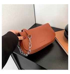 Detail of caramel leather saddle bag featuring fashion & bags text and silver chain strap