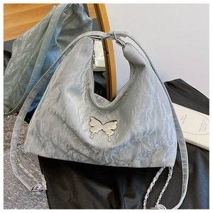 Detail of silver metallic crinkled fabric and mirror butterfly ornament on shoulder bag