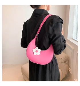 Dettaglio borsa a mezzaluna rosa con ciondolo a fiore bianco e logo del marchio