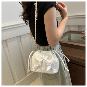 Detail of white PU bucket bag with satin bows and leather woven chain strap