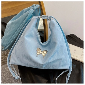 Close-up of light blue Y2K style shoulder bag with metallic butterfly and chain detail