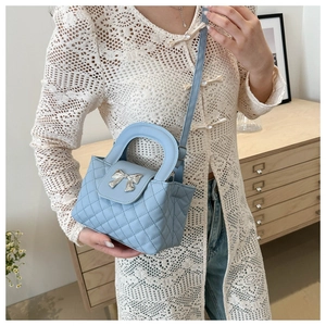 Détail du sac à main matelassé bleu clair avec nœud argenté, poignée et bandoulière