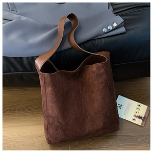 Dettaglio della borsa tote in pelle scamosciata marrone scuro su pavimento in legno