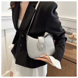 Detail of silver metallic underarm bag with sparkling square rhinestone buckle on flap