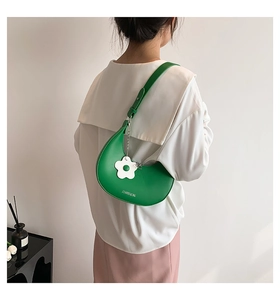 Borsa a mezzaluna verde con ciondolo a fiore indossata a spalla da una modella