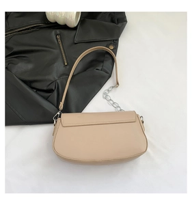 Close-up of beige saddle bag with silver chain strap and smooth faux leather finish