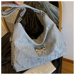 Macro view of silver pleated hobo bag with a metallic butterfly clasp and chain detail