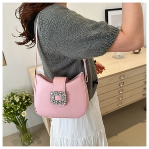 Gros plan d'un sac à bandoulière rose en cuir avec boucle carrée ornée de strass brillants