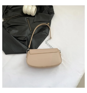Detail of beige faux leather saddle bag featuring silver metal chain decorative strap