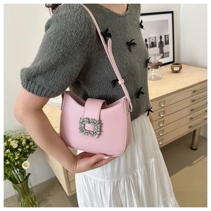 Gros plan du sac sous le bras en cuir rose avec boucle carrée ornée de strass brillants