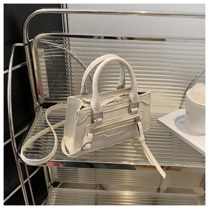 Détail du sac en cuir blanc avec fermetures éclair métalliques et longs glands décoratifs