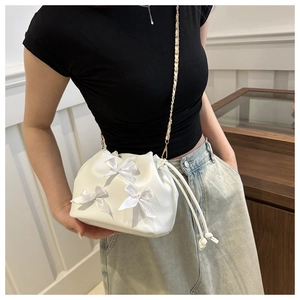 Détail du mini sac à cordon blanc avec nœuds en soie et bandoulière en chaîne