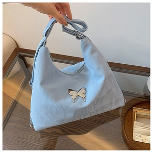 Detail of light blue hobo bag with silver butterfly ornament and adjustable strap