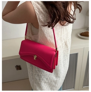 Detail of rose pink crossbody bag showing accordion side gussets and gold buckle