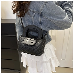 Détail d'un sac à main matelassé noir avec boucle nœud argenté et poignée robuste