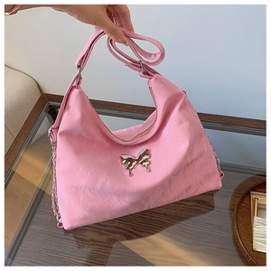 Detailed view of pink shoulder bag featuring a silver butterfly buckle and pleated texture
