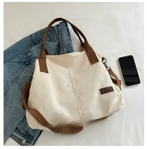 Detailed top view of off-white canvas tote bag with brown straps and fashion label