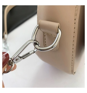Detailed close-up of the silver hardware and D-ring on a beige leather saddle bag