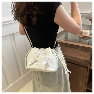 White drawstring bucket bag with satin bows and golden chain strap for women