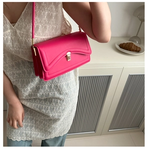 Detail of fuchsia leather crossbody bag featuring a golden rectangular clasp lock