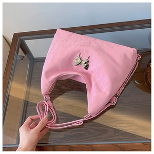 Detail of pink pleated crescent bag with metallic silver butterfly charm and chain