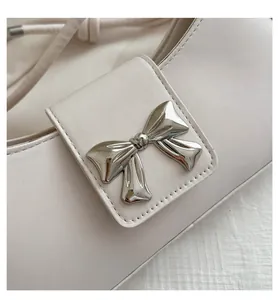 Dettaglio della borsa baguette in pelle bianca con fibbia decorativa a fiocco argento