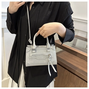 Détail du petit sac bleu clair avec de longues tirettes de fermeture décoratives